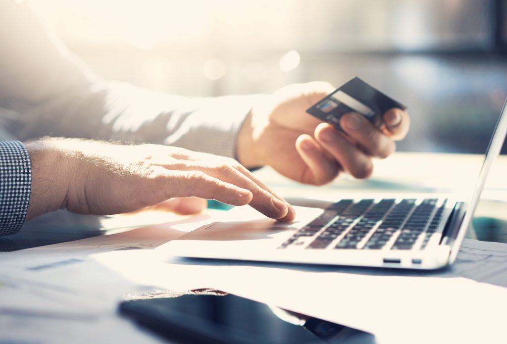 Man Holding Credit Card at Laptop